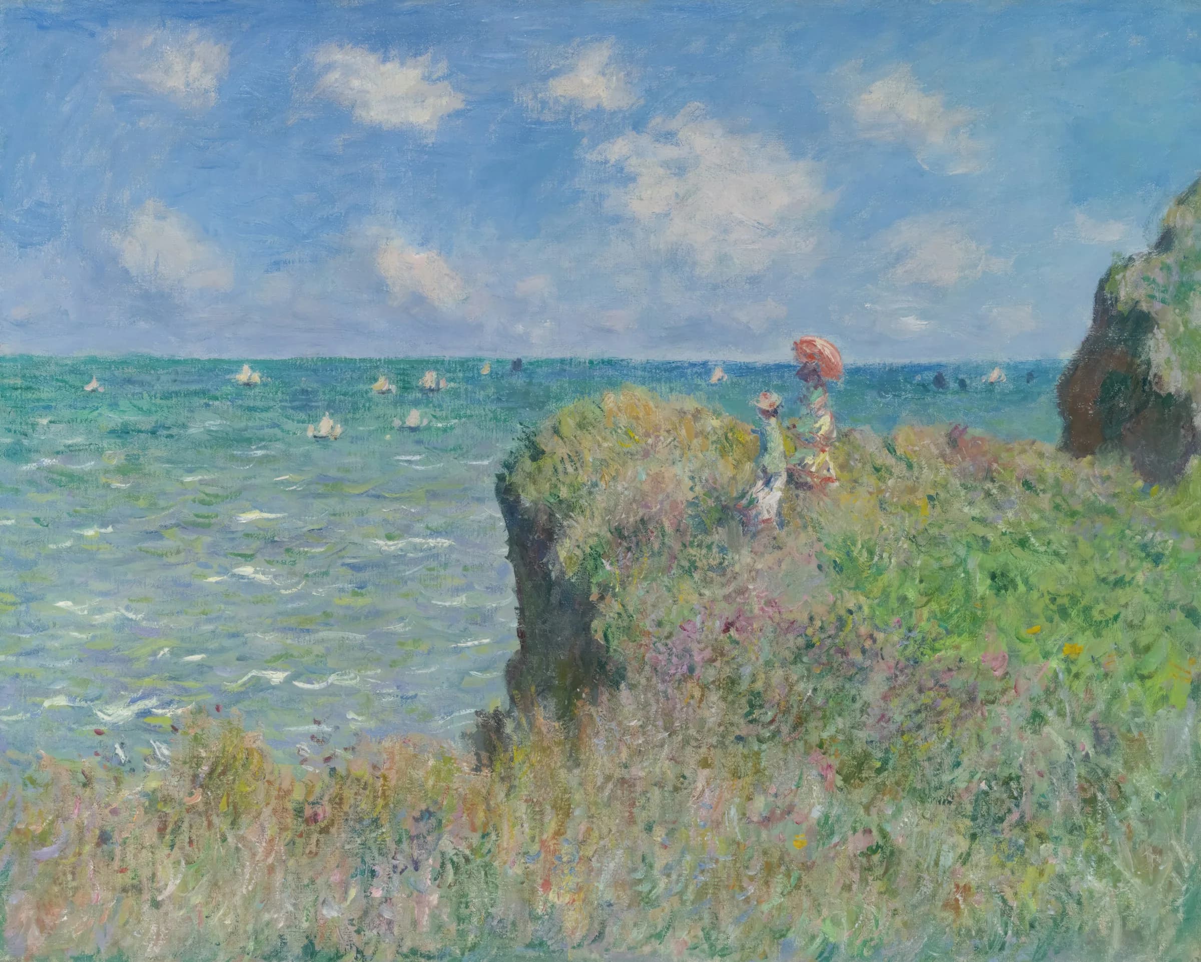 Two people looking out at ocean from grassy cliff